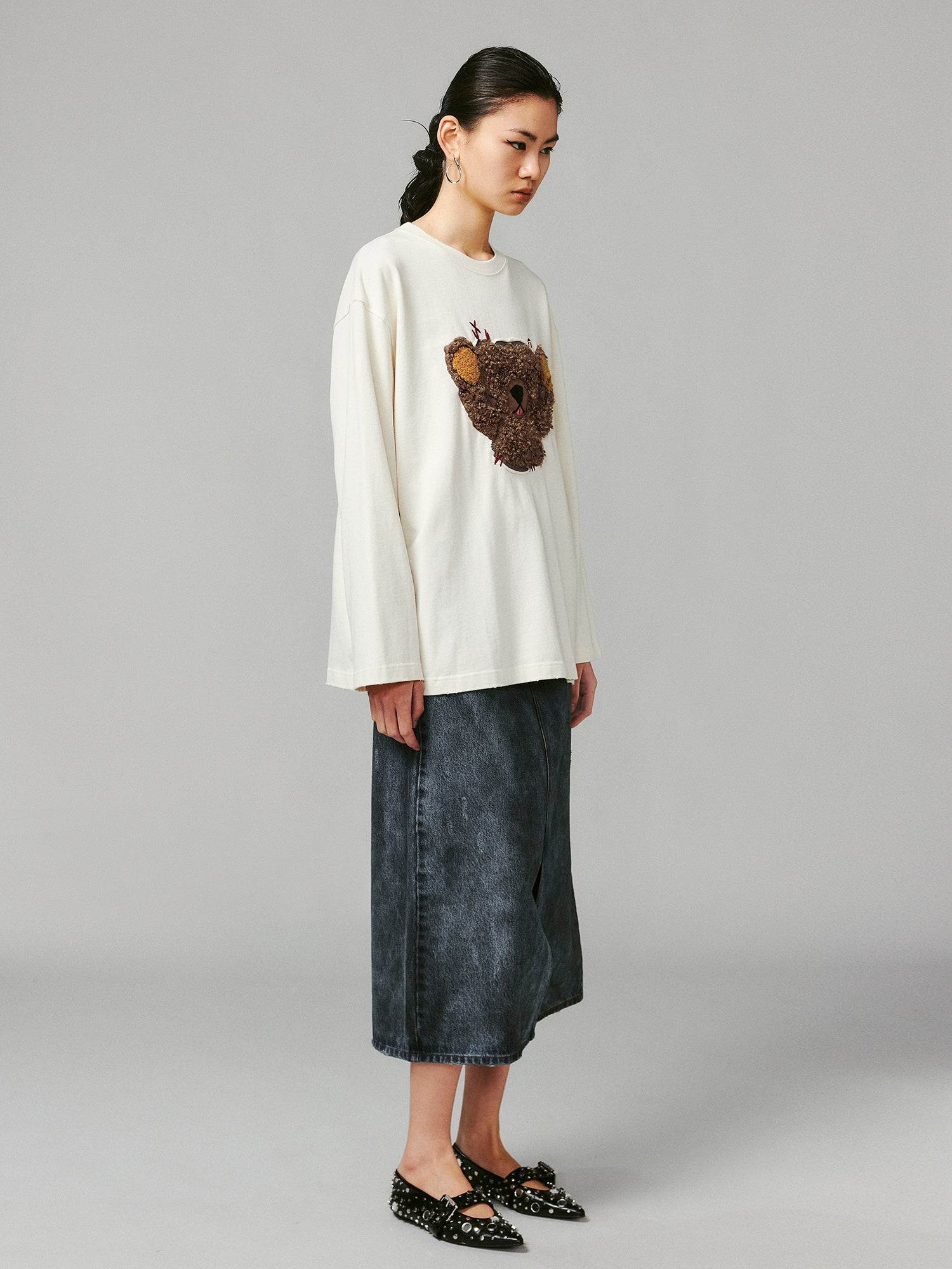 Teddy bear peeking through long-sleeve T-shirt