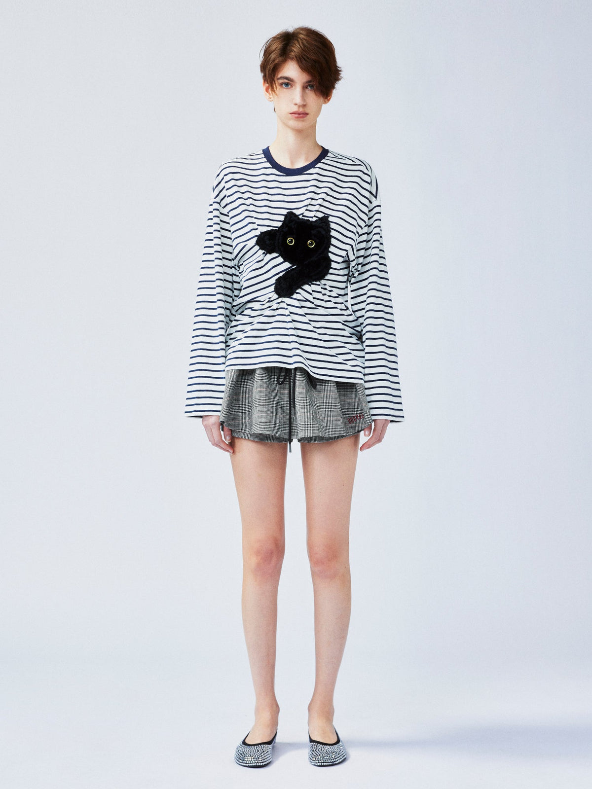 Playful cat scratching bedsheet striped T-shirt