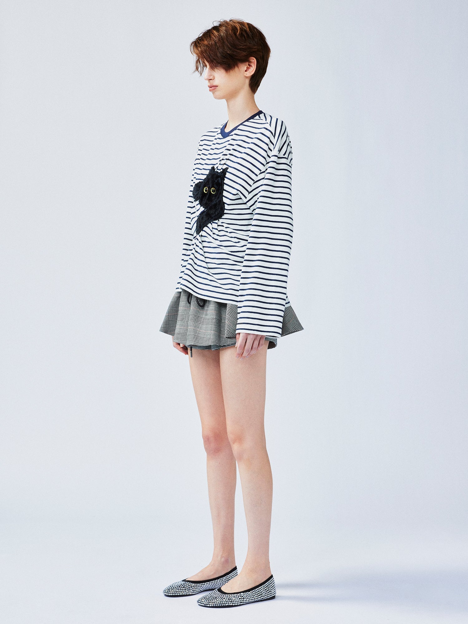 Playful cat scratching bedsheet striped T-shirt