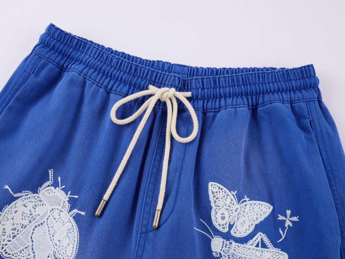Lace insect and floral motif curved denim pants
